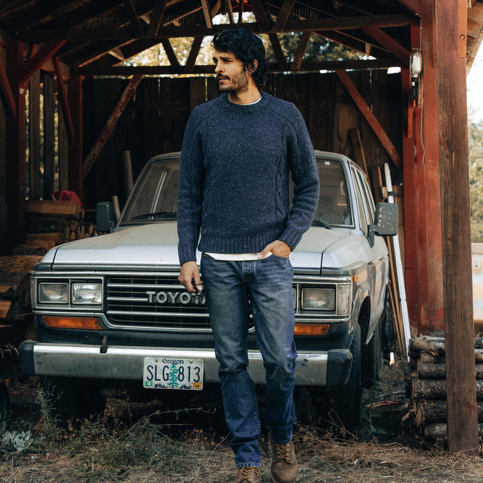 fit model next to a car wearing The Topside Sweater in Navy Donegal