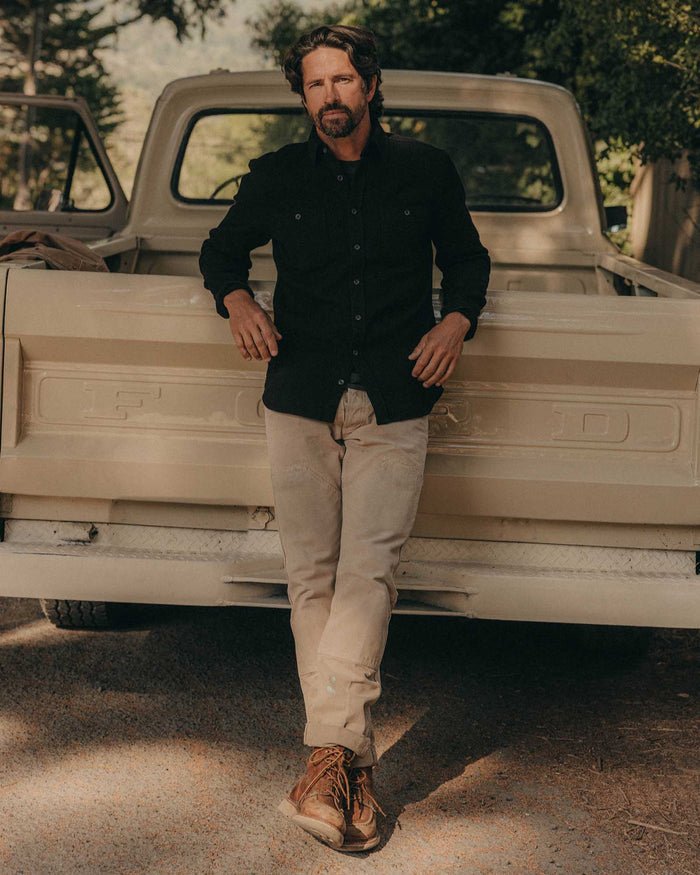 fit model leaning against a car wearing The Utility Shirt in Black Indigo Sashiko