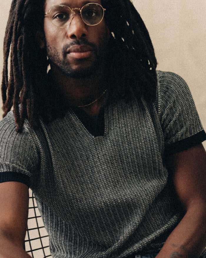 fit model sitting wearing The Valencia Sweater Polo in Coal Scallop