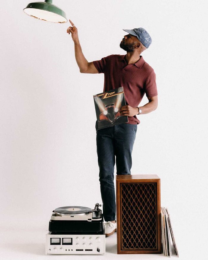 fit model holding a record wearing The Valencia Sweater Polo in Dried Cherry Rib