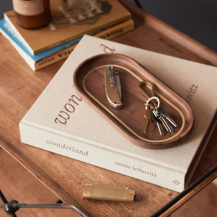 The Valet Tray in Walnut and Brass on a book
