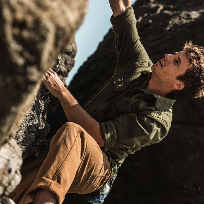 The fit model climbing boulders next to the ocean