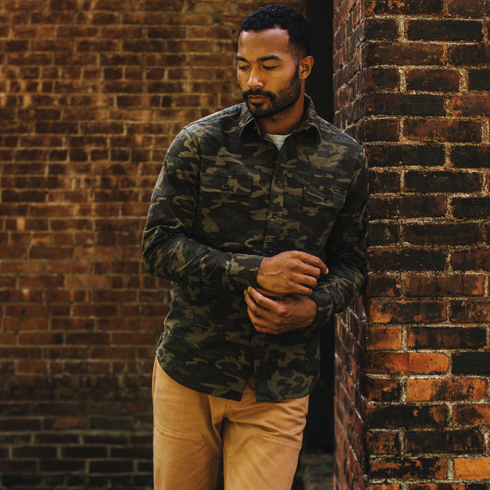 fit model leaning against the wall wearing The Yosemite Shirt in Trail Camo