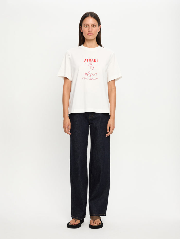 Person wearing a white t-shirt with red text and dark pants on a white background
