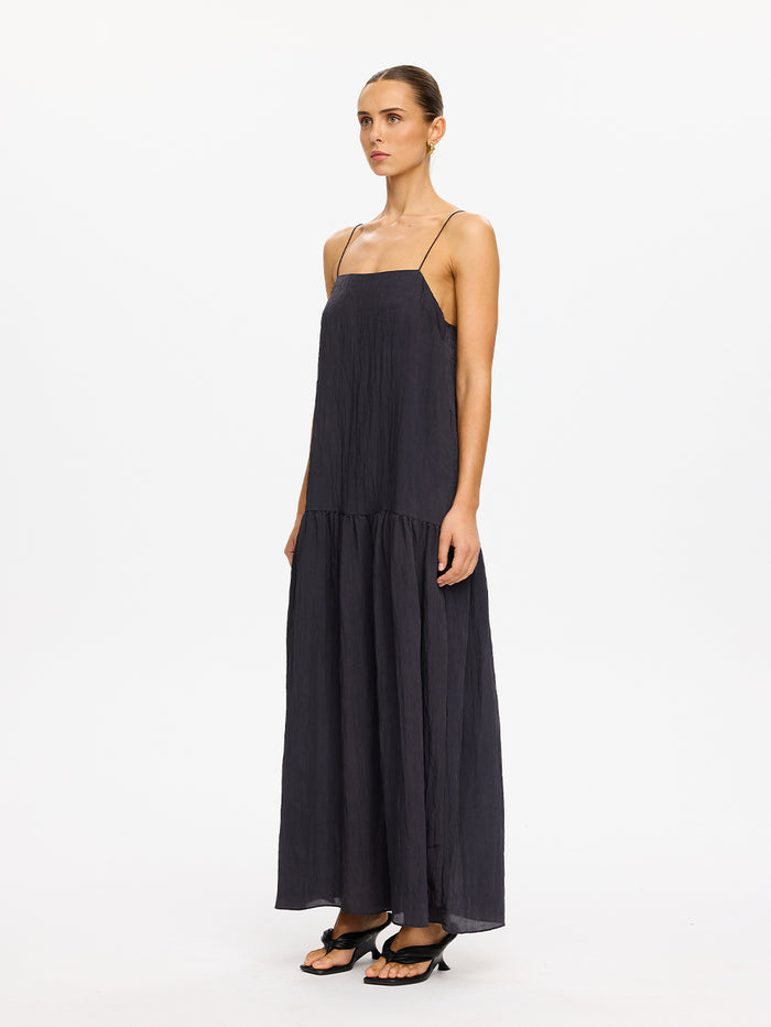 KIVARI Umi Maxi Dress in Charcoal – full-length side view of model wearing women's charcoal spaghetti strap tiered maxi dress