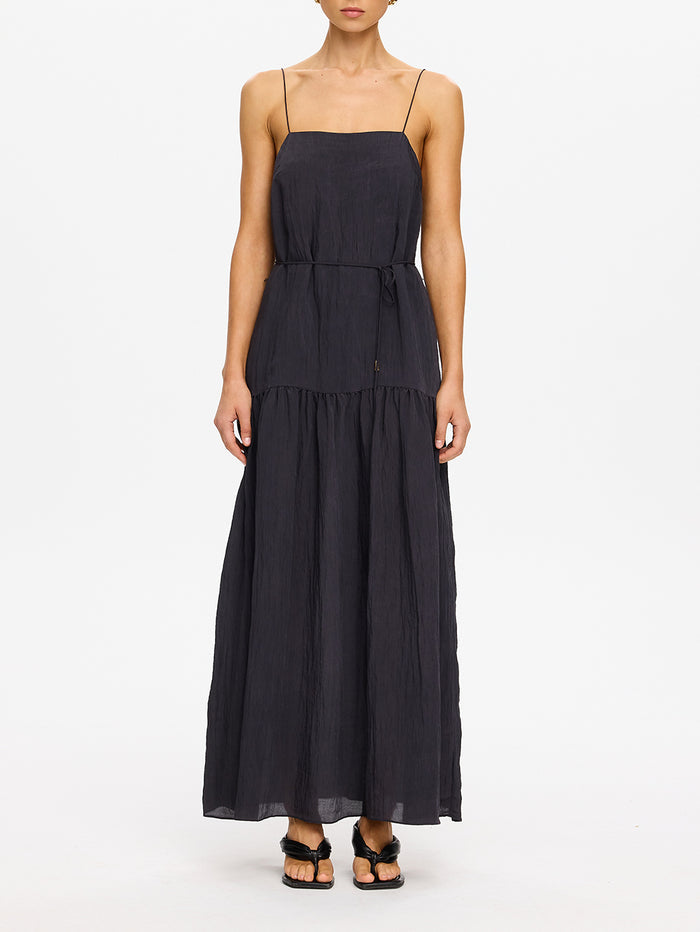 KIVARI Umi Maxi Dress in Charcoal – model wearing women's charcoal spaghetti strap tiered maxi dress with drawstring waist detail